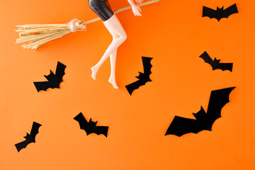 A Halloween witch rides a broom. The concept of celebrating a horror holiday. Orange background of...