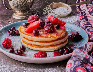 Healthy breakfast of pancakes with mixed fruits and honey.