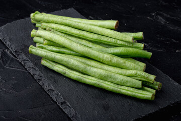 Fresh green French beans, on stone board, on black background