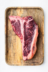 Raw fresh beef t-bone steak drya aged cut, on wooden tray, on white stone  background, top view flat lay