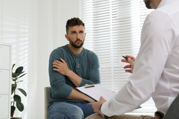 Psychotherapist working with drug addicted man indoors