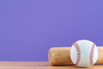 Close up baseball and baseball bat on wooden table with purple copy space background, sport concept