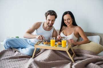 cheerful couple having breakfast in bed