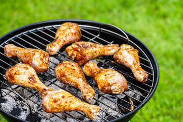 Chicken Drumsticks Legs Grilled on Charcoal BBQ in Backyard Garden at Summer Picnic