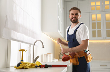 Plumber with plunger near clogged sink in kitchen