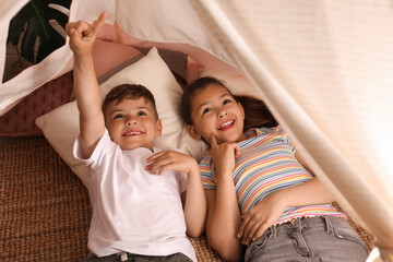 Cute little children lying in toy wigwam at home © New Africa