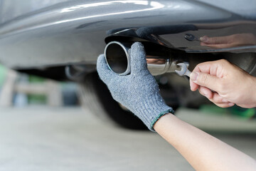 Hand a man catch car exhaust and use open-end wrench for service in concept maintenance car in...