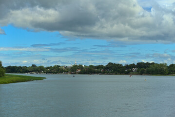 Islands of Boucherville national park in Lawrence (Laurent) River, Montreal, QC on a cloudy summer day. The trees and grass on the river banks. The marina od Boucherville at the background.