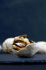 Nuts. Walnut kernels and whole walnuts on dark stone table. Black background. Top view, flat lay with copy space.