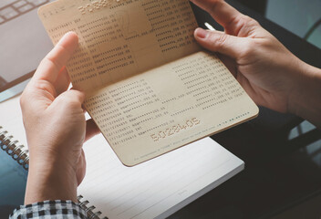 Naklejka premium Someone hands holding saving account passbook. financial report passbook saving money finance and business rich concept. financial problems, unemployment due to pandemic covid-19.