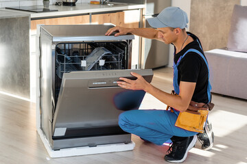 Worker repair dishwasher at home.