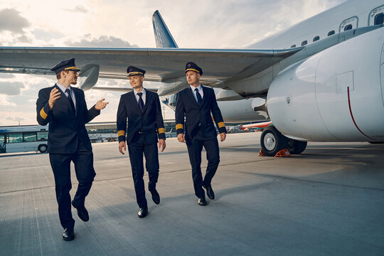 Three elegant aviators going along the runway