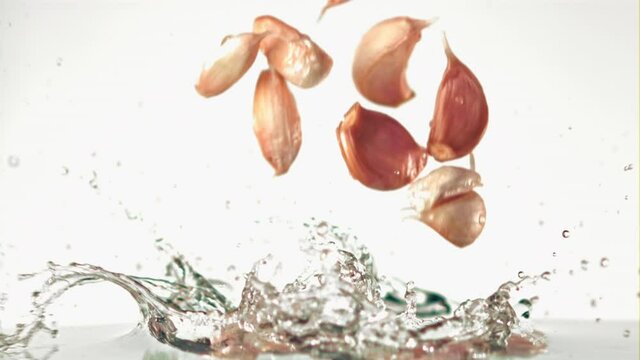 Super slow motion garlic falls on the water on a white background. Filmed on a high-speed camera, 1000 fps.High quality FullHD footage