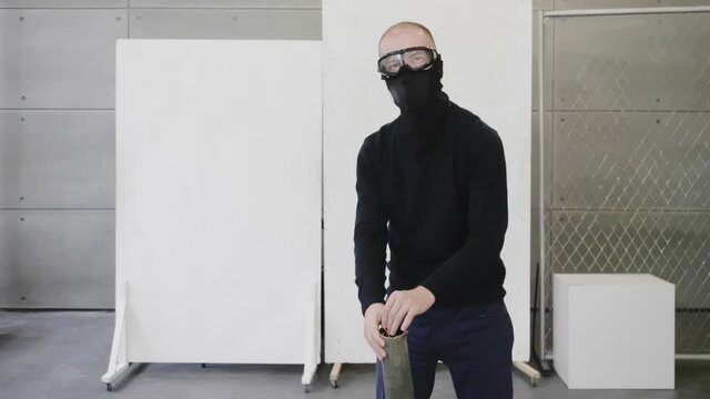 Strange man in black mask and glasses shoves bunch of stationery rubber bands into pipe of vacuum cleaner. Office battle war, game. Person imitates cowboy. Funny situation before duel