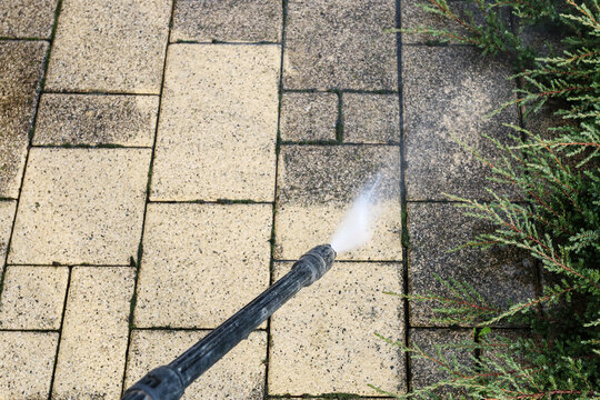 Cleaning dirty paving stones in the garden with a pressure washer.