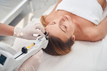 Pretty woman during hair treatment procedure in clinic