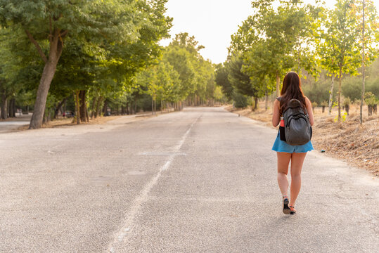 Young Caucasian Girl Walking Backwards In The Park.