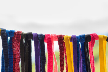 shoelaces tied to a wire, hanging down, with white background, many colors