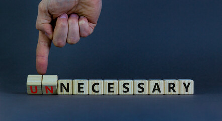 Necessary or unnecessary symbol. Businessman turns wooden cubes and changes the word Unnecessary to...