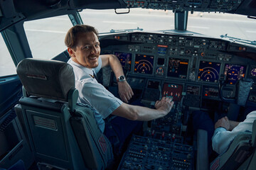 Fototapeta premium Joyful chief pilot posing for the camera in the cockpit