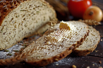 Freshly baked bread with seeds and butter on a wooden board. Selective focus