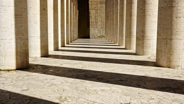 The sun shines through the stone pillars, the light and shadow moving on the stone floor and walls, time-lapse.