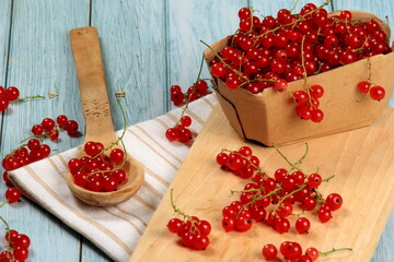 Red currant on blue wooden tablebackground. Cup and jar with fresh red currants (ribes rubrum).