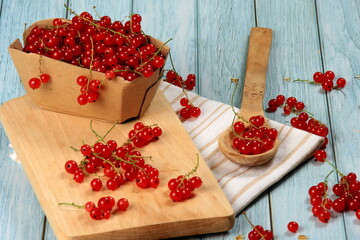 Red currant on blue wooden tablebackground. Cup and jar with fresh red currants (ribes rubrum).