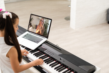 Fototapeta na wymiar little girl play piano in class education with laptop in home online learning in covid-19 crisis quarantine