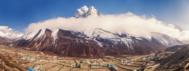 Dingboche mountain village in Imja Khola river valley and view of Ama Dablam mount at sunset in clouds. Sagarmatha National Park, Nepal. Amazing panoramic view