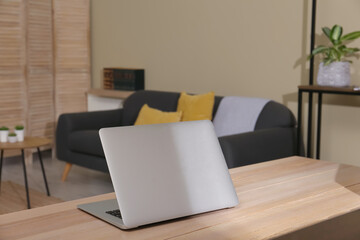 Comfortable workplace with laptop on wooden table in room. Interior design