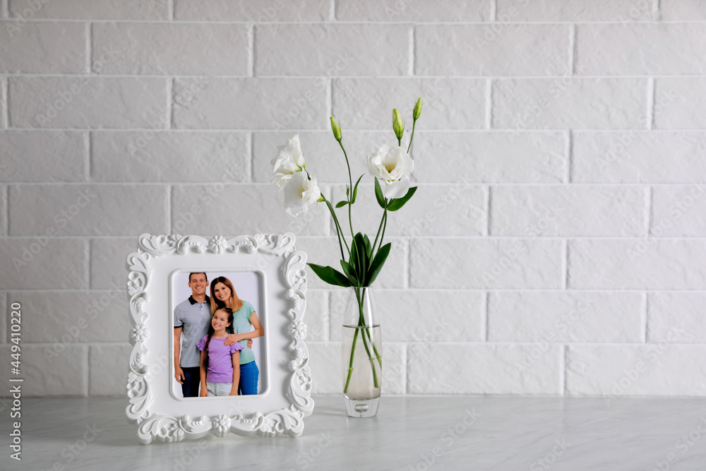 Wall mural Framed family photo near beautiful bouquet on white table