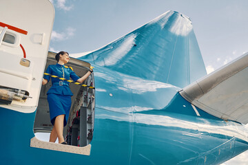 Smiling pleased flight attendant looking out of a parked aircraft