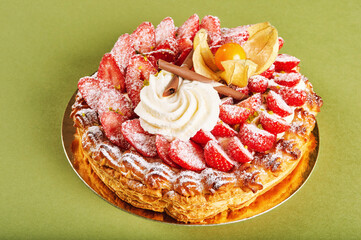 French dessert, strawberry tart with whipped cream topped with powdered sugar, green background