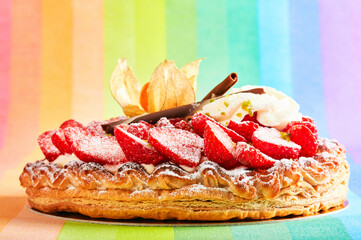 French dessert, strawberry tart with whipped cream topped with powdered sugar, rainbow background