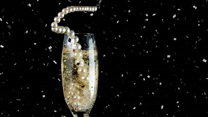 Confetti falling over pearl beads falling in champagne glass against black background - Powered by Adobe