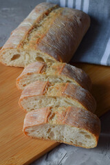 slices of delicious homemade sliced ciabatta bread on a wooden board on a gray background . Close-up.top view.