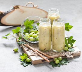 Drink, gooseberry smoothie in a tall glass bottle with a straw on a light gray background