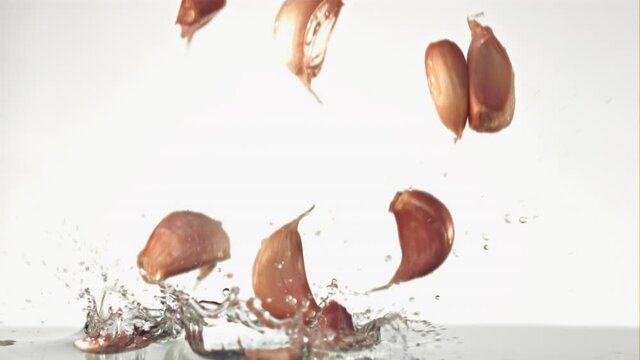 Super slow motion garlic cloves fall on the water with splashes. Filmed on a high-speed camera at 1000 fps. High quality FullHD footage
