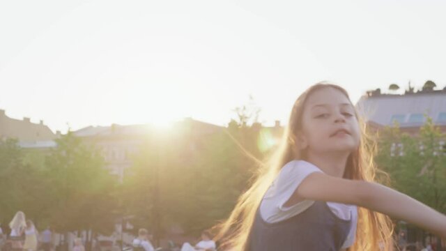 Cute preteen longhair girl dancing with at sunset park.