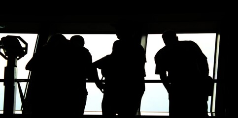 silhouettes of tourists at wide window