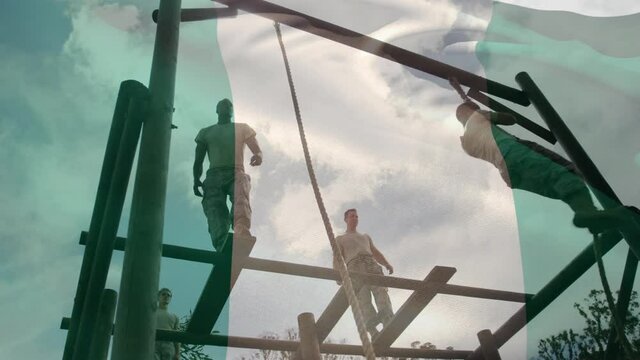 Waving nigeria flag against male soldiers rope climbing during obstacle course at boot camp