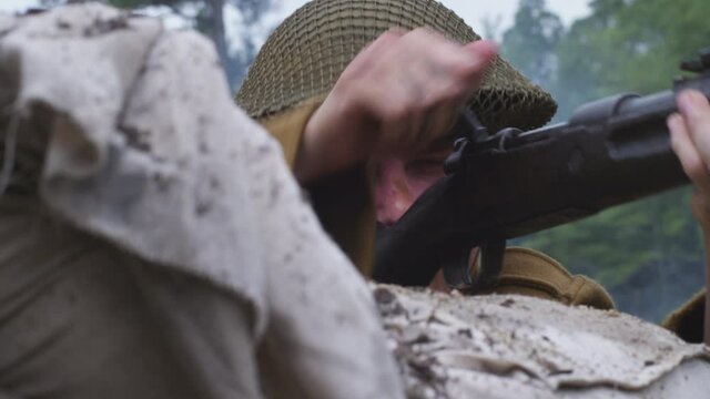 World War 1 British soldier repeatedly firing bolt action rifle on the battlefield. Smoke in the air (Shot on RED) 4K