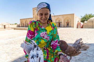 girl with doves on the background of the ancient city. Bukhara, Uzbekistan