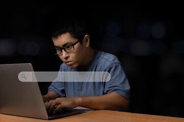Young man with eye glasses browsing at his computer laptop to searching information.