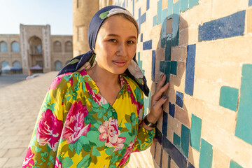 Muslim girl with a scarf on her head at the gate of the old mosque. Bukhara, Uzbekistan.