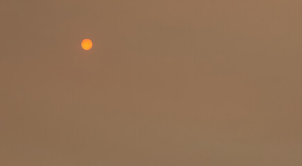 Sun shining through a cloud of smoke caused by forest fire