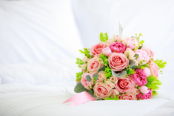 A bouquet bunch of colorful fake fabric flowers on white bed cover with copy spce