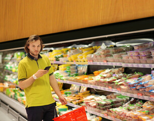 Young man shopping in supermarket, reading product information