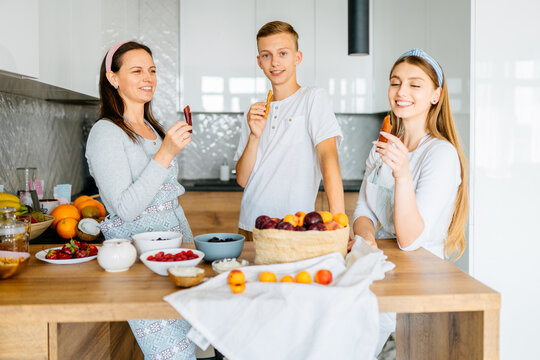 Cooking Lesson. Happy Mom Teaching Adult Daughter And Teen Son Prepare Healthy Nutrition, Caucasian Mother With Two Grown Children Talking Smiling Engaged In Useful Activity At Kitchen.